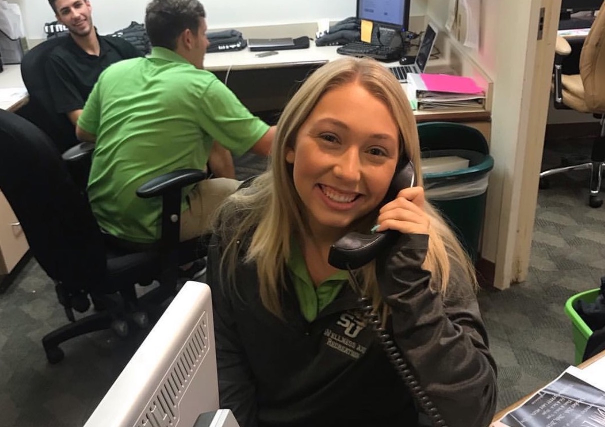 One student working at a desk and talking on the phone.